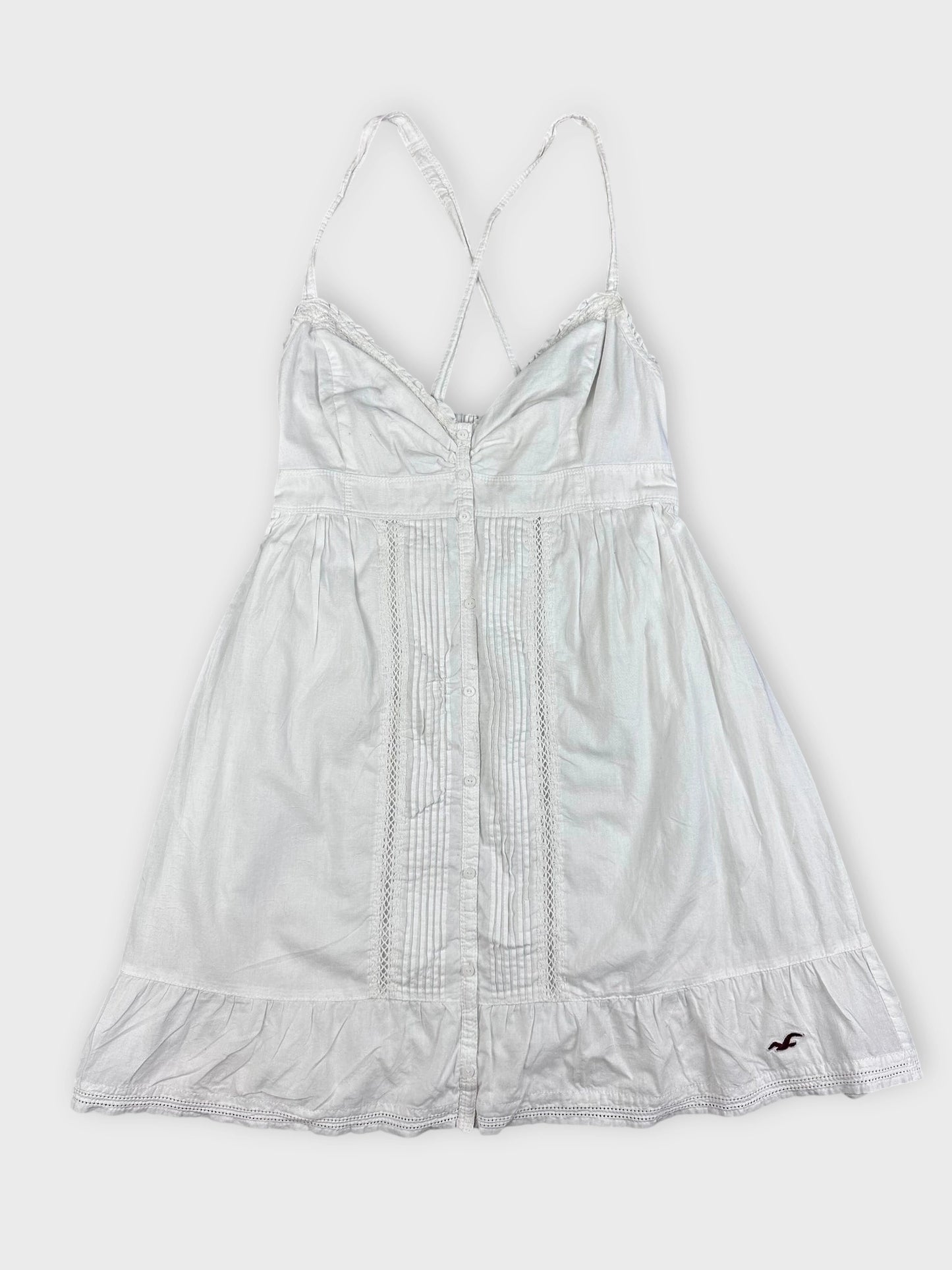 Detail view of a white cotton strap dress featuring decorative button details.