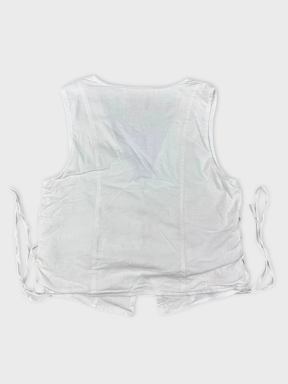 Back view of a white linen top featuring side lace-up detail.