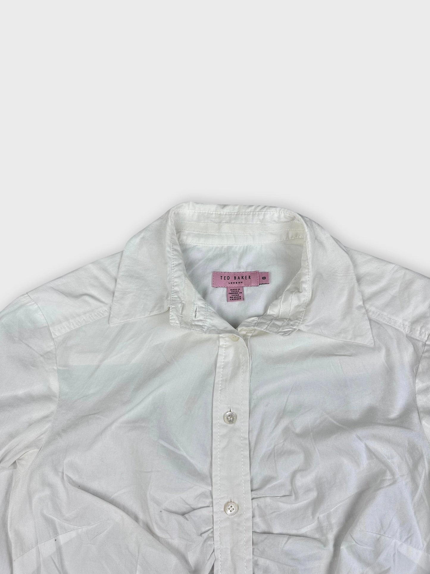 Detail view of a white long sleeve button up shirt with a classic collar.