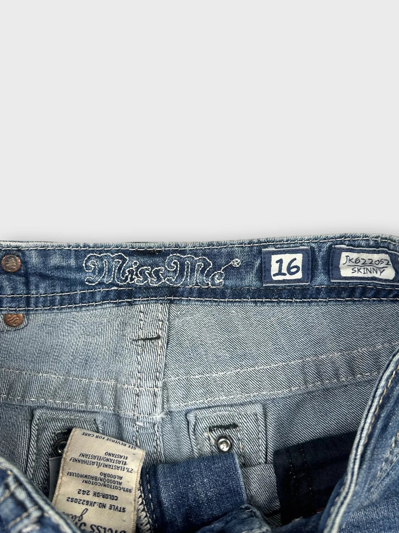 Detail view of classic blue denim skirt with distressed edges and logo