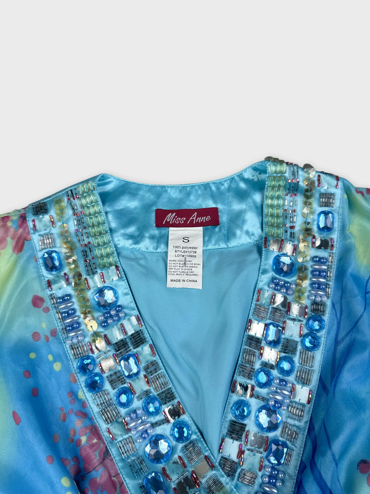 Detail view of a colourful blue top with beaded embellishments.