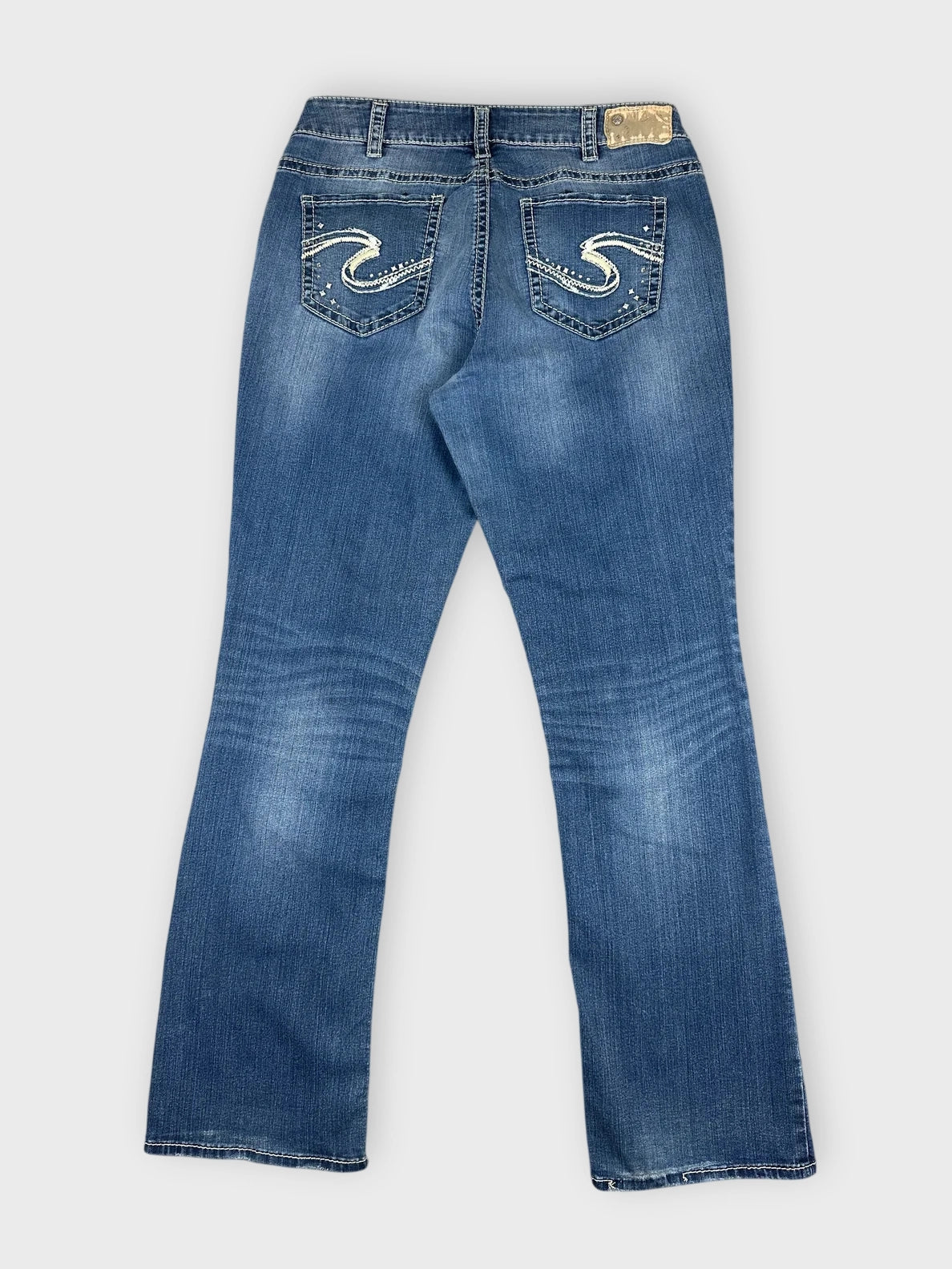 Detail view of cool blue denim jeans with flare and decorative back pockets.