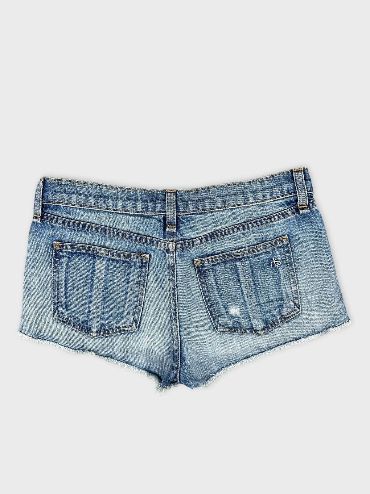 Back view of denim shorts in classic blue with distressed details.
