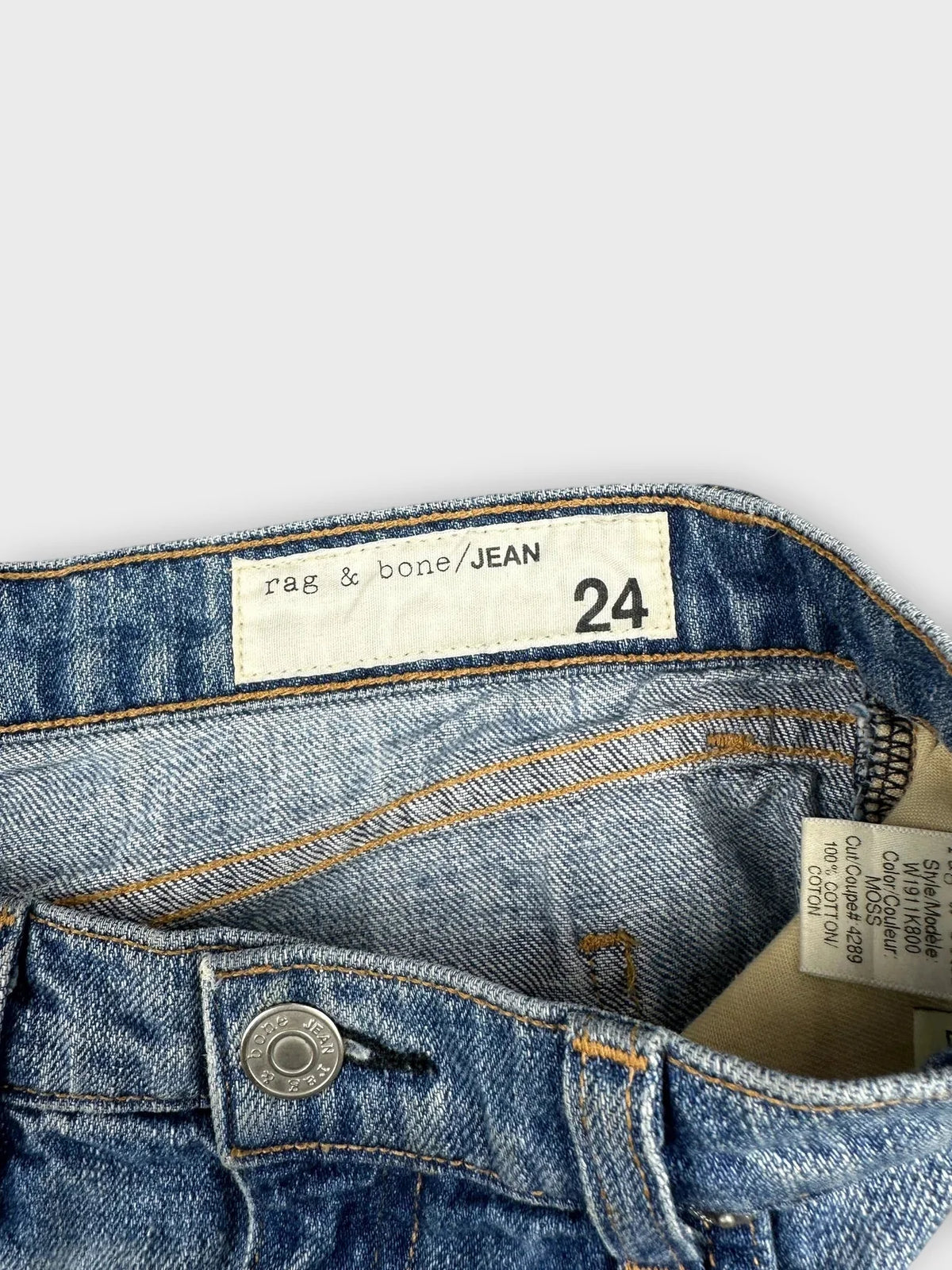 Detail view of blue denim shorts featuring distressed detail and brand tag.