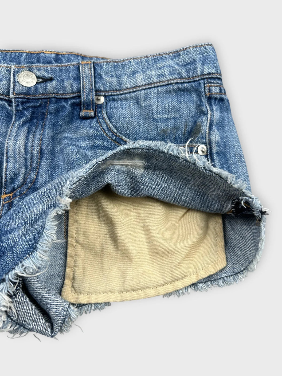 Detail view of blue distressed denim shorts with frayed hem.