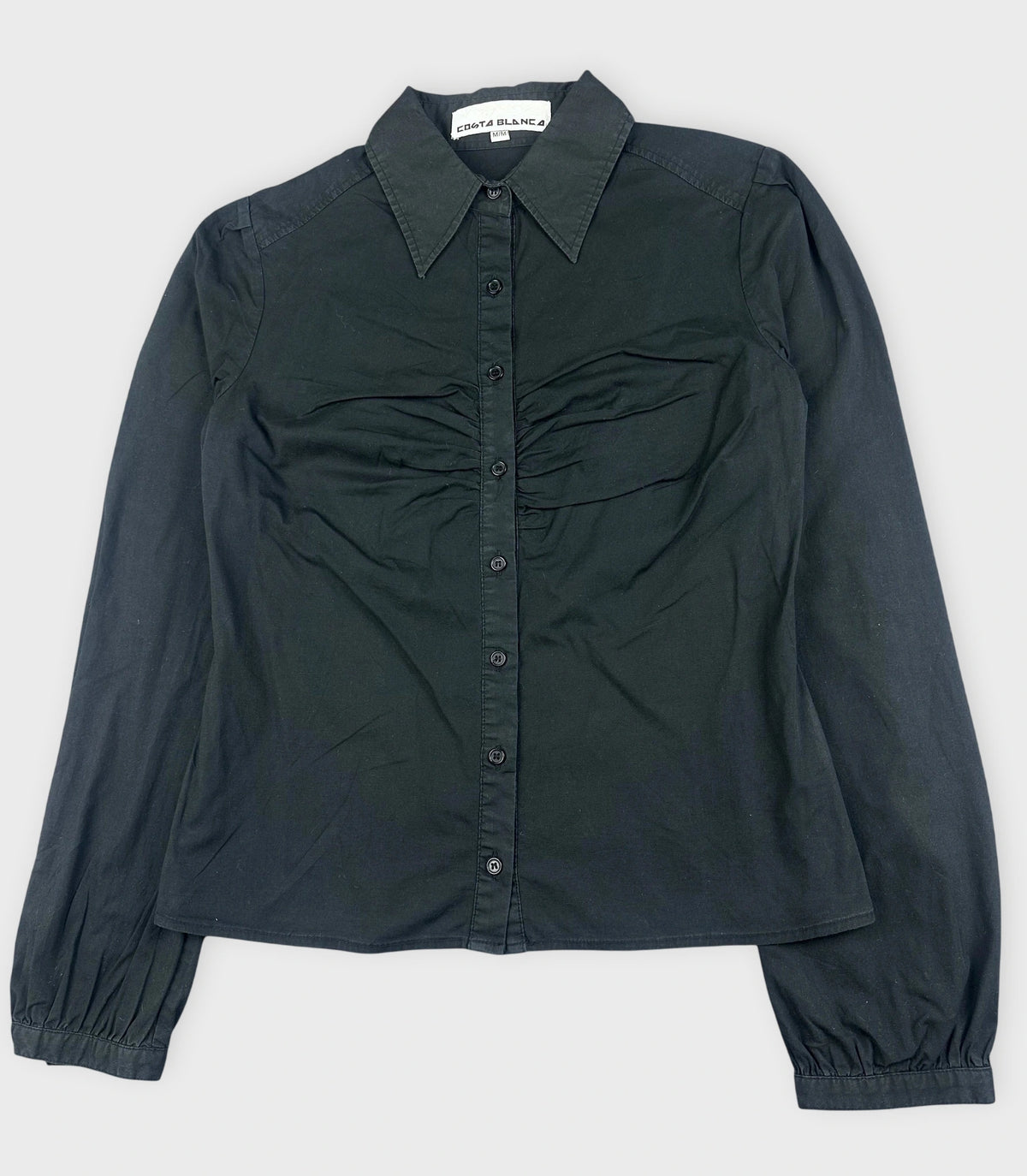 Detail view of a black button-up shirt featuring ruched front detail.