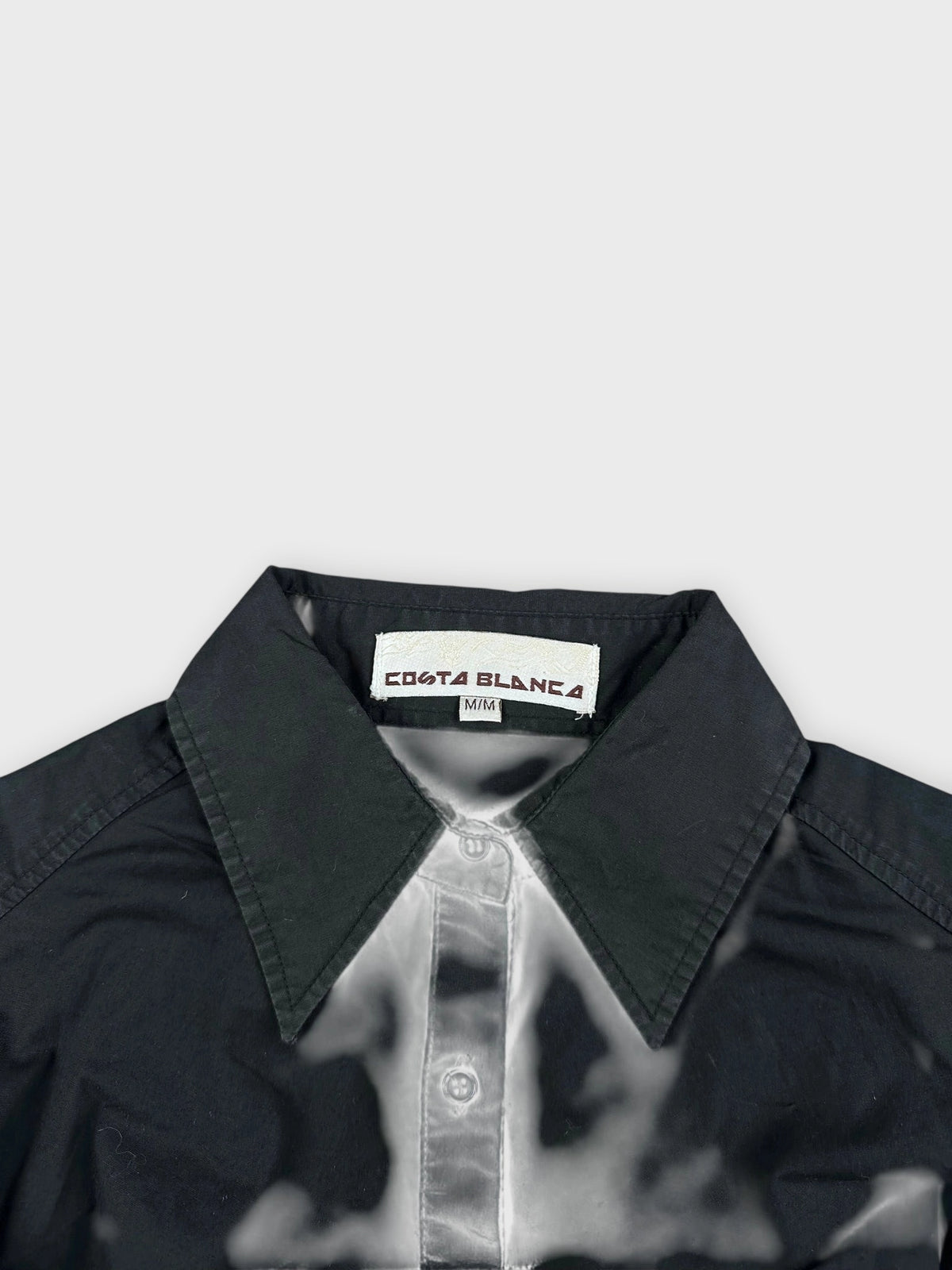 Detail view of black button-up shirt with subtle ruching.