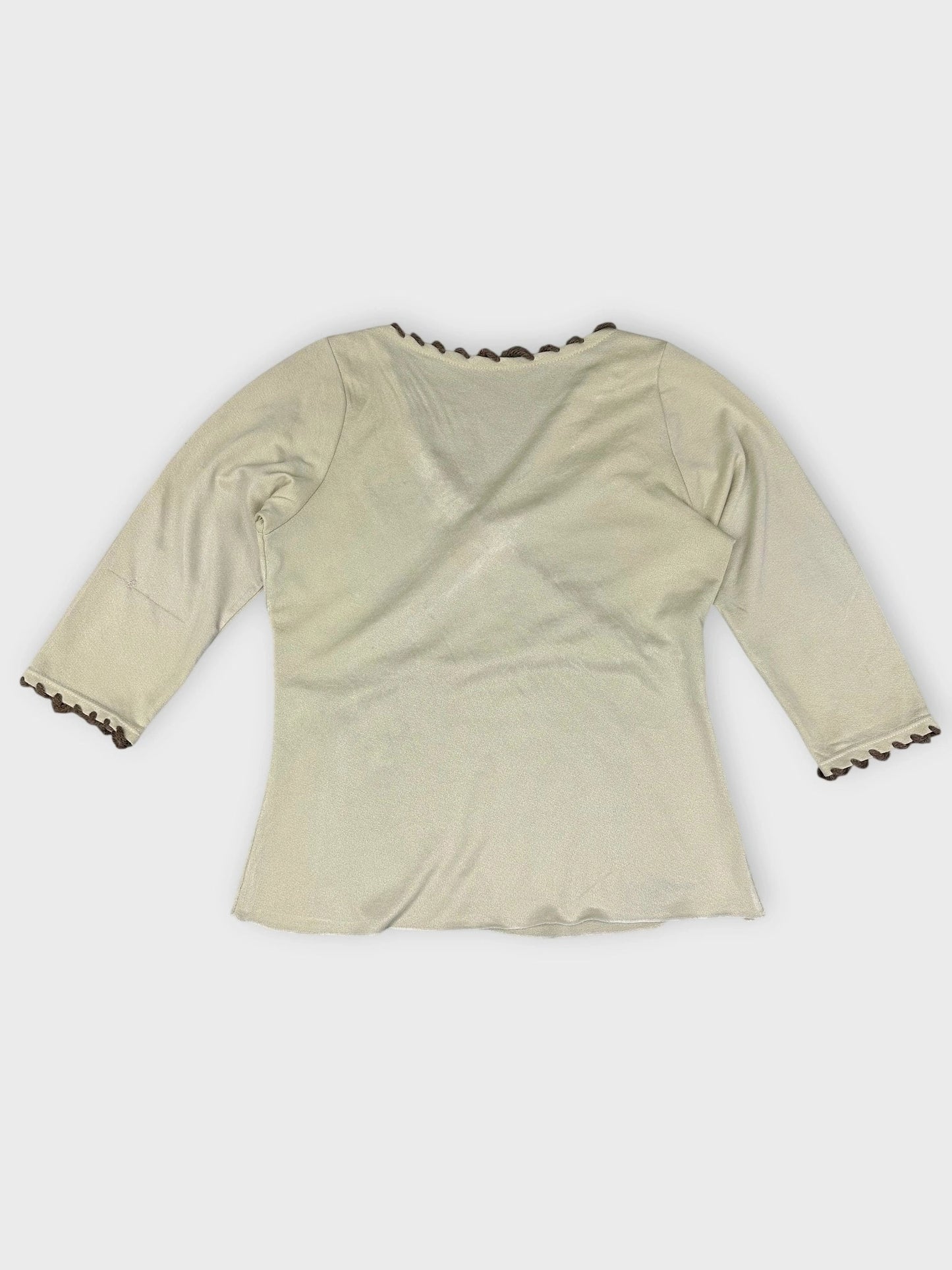 Back view of cream floral wrap top with scalloped edge detail.