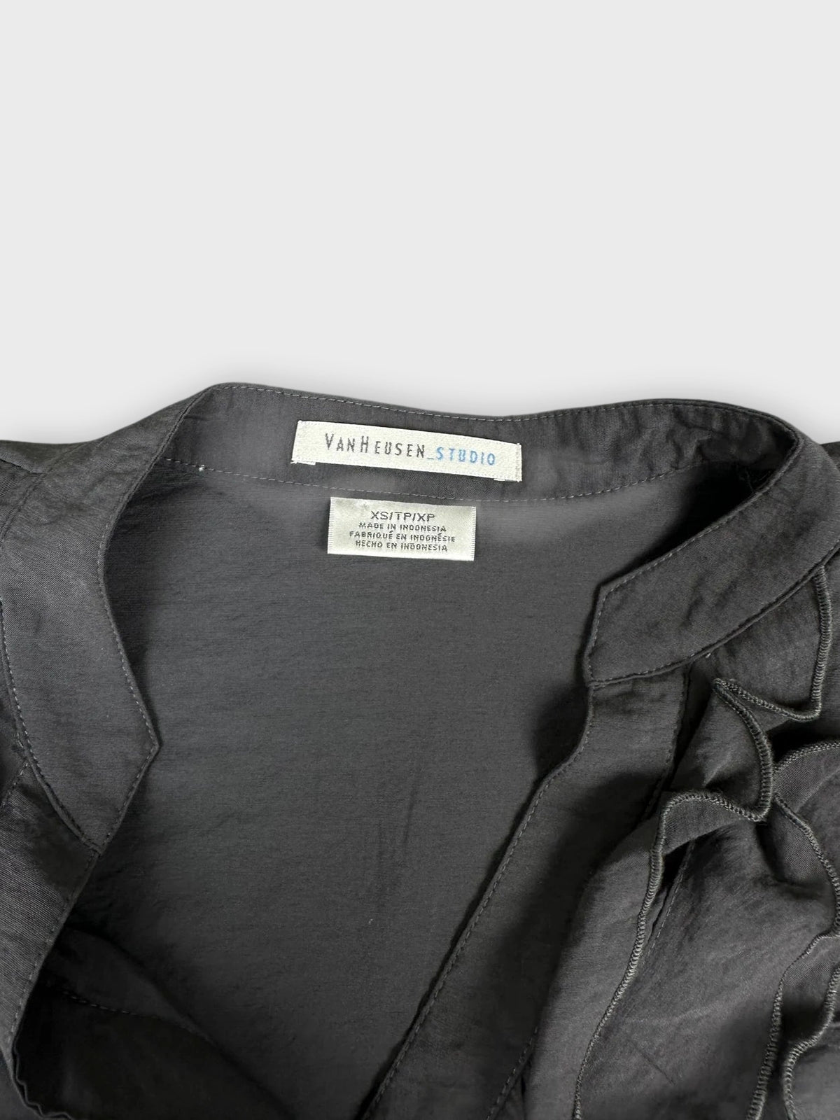Detail view of a dark gray button-up shirt with ruffled trim.