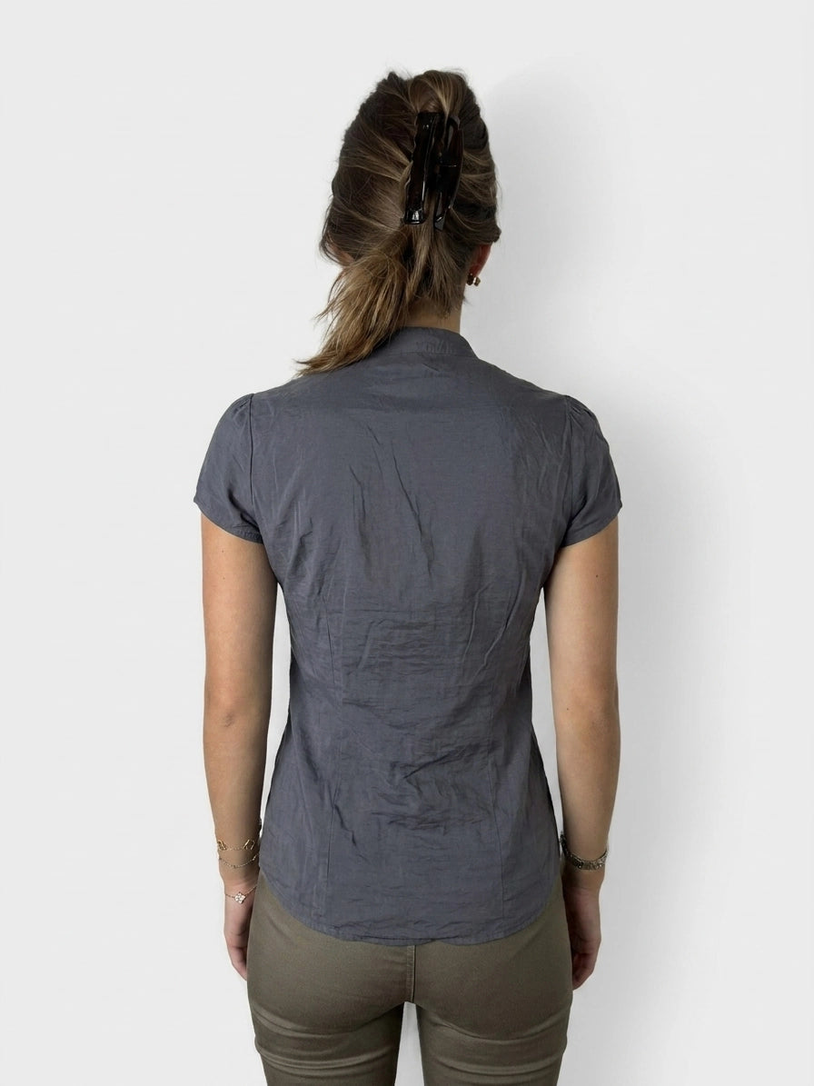 Back view of a dark gray ruffled button-up shirt with a fitted shape.
