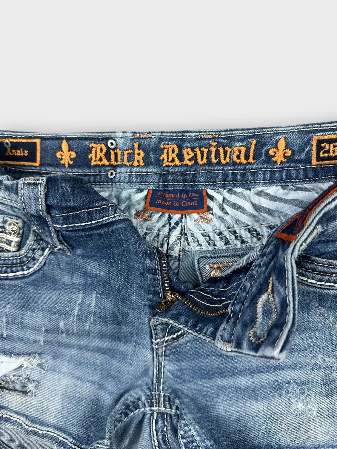 Detail view of distressed denim skirt featuring blue wash and zip detail.