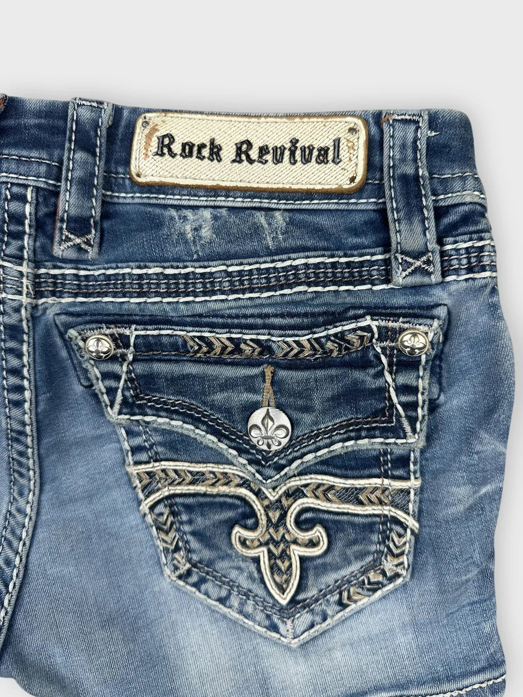 Detail view of a distressed denim skirt in blue with decorative stitching.