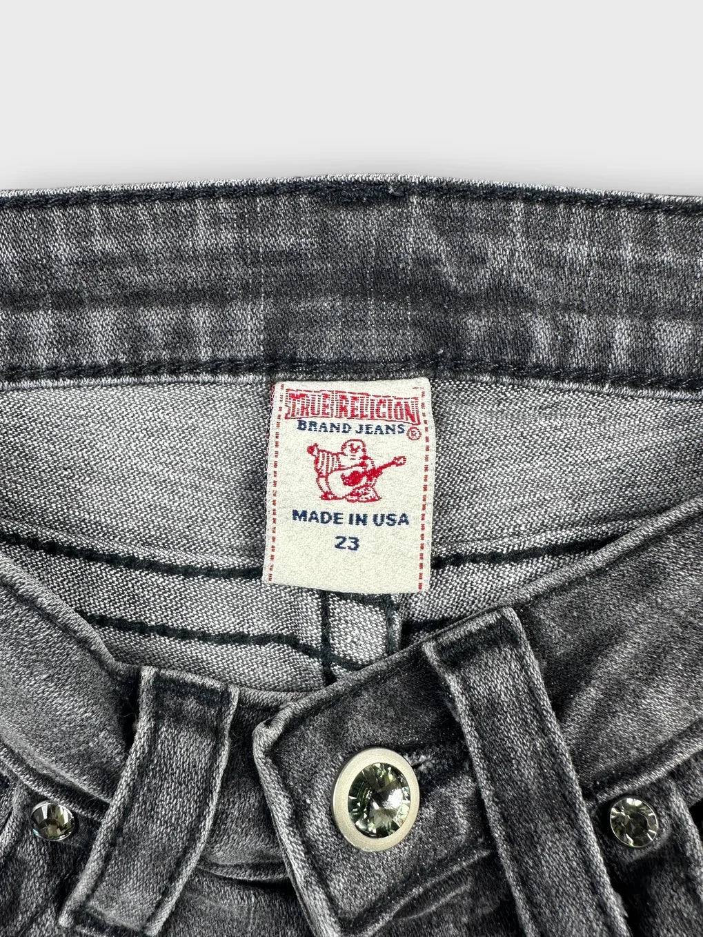 Detail view of black denim shorts featuring a unique button and waistband design.
