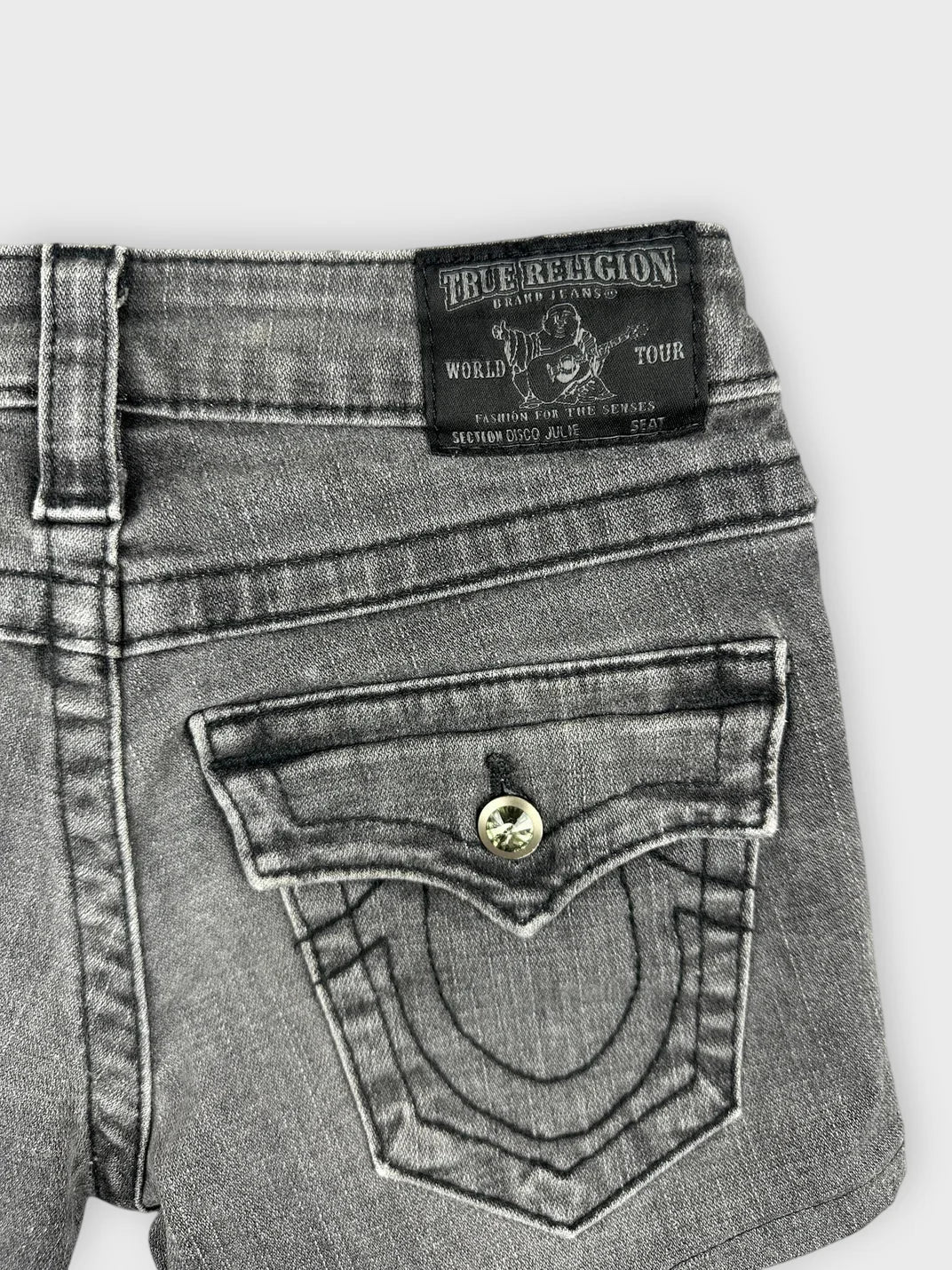 Detail view of edgy black denim shorts with unique back pocket stitching.