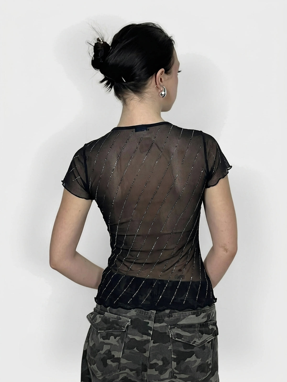 Back view of a black shimmer top with ruffles and diagonal sparkly lines.