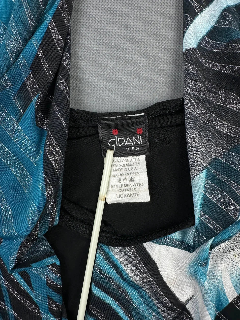 Detail view of an edgy blue halter top featuring graphic print and leather belt.