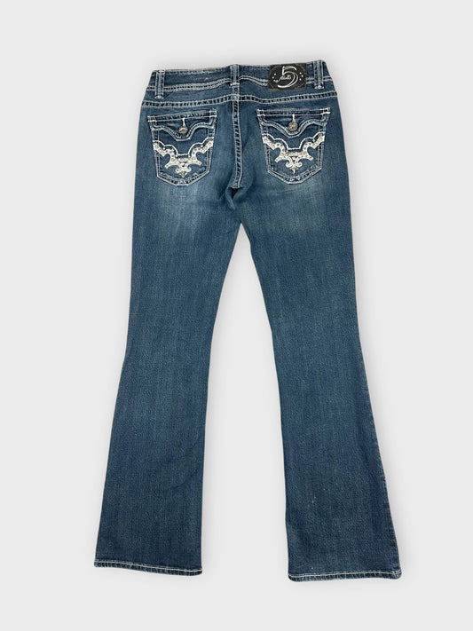Back view of flared denim jeans in dark wash with decorative pockets.