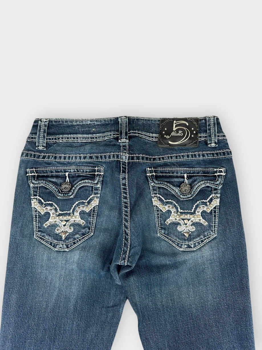 Detail view of dark blue flared jeans with decorative stitching on back pockets.