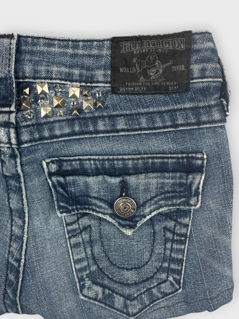 Detail view of blue denim shorts featuring studded details and pocket design.