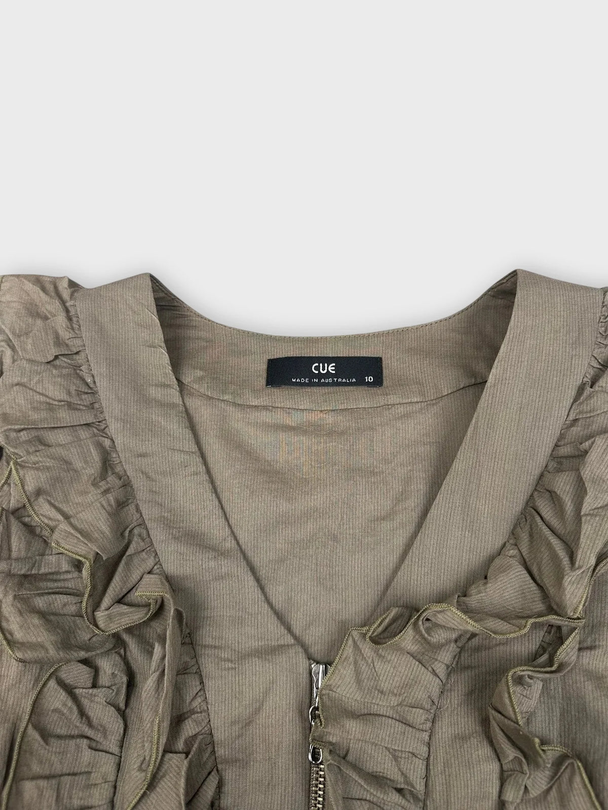 Detail view of a green ruffle zip top with textured trim.