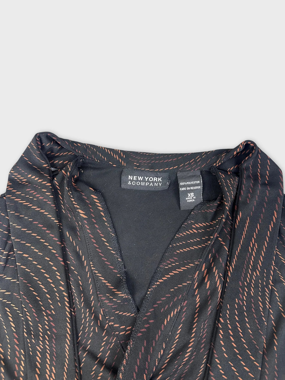 Detail view of elegant black cowl neck top featuring swirl pattern.