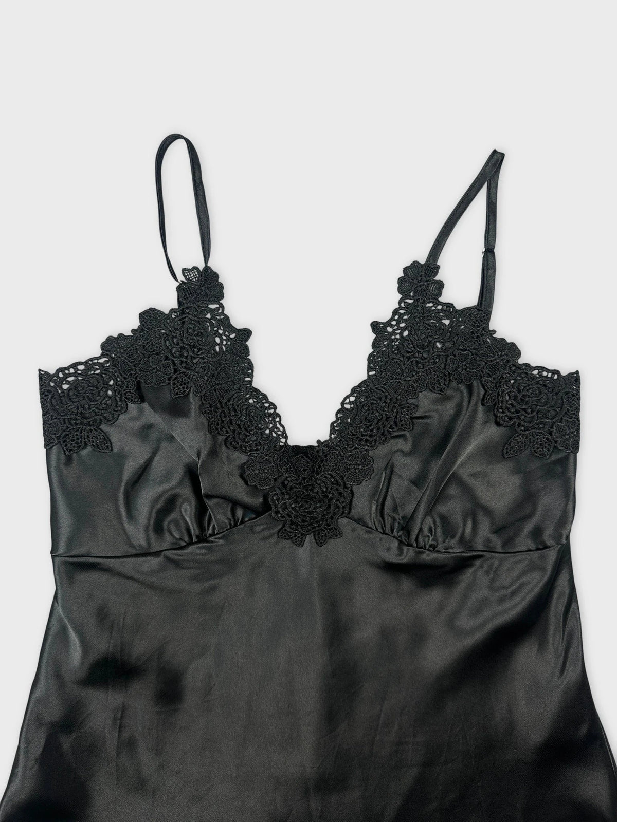 Elegant black silk camisole with lace detail, shown in a detail view.
