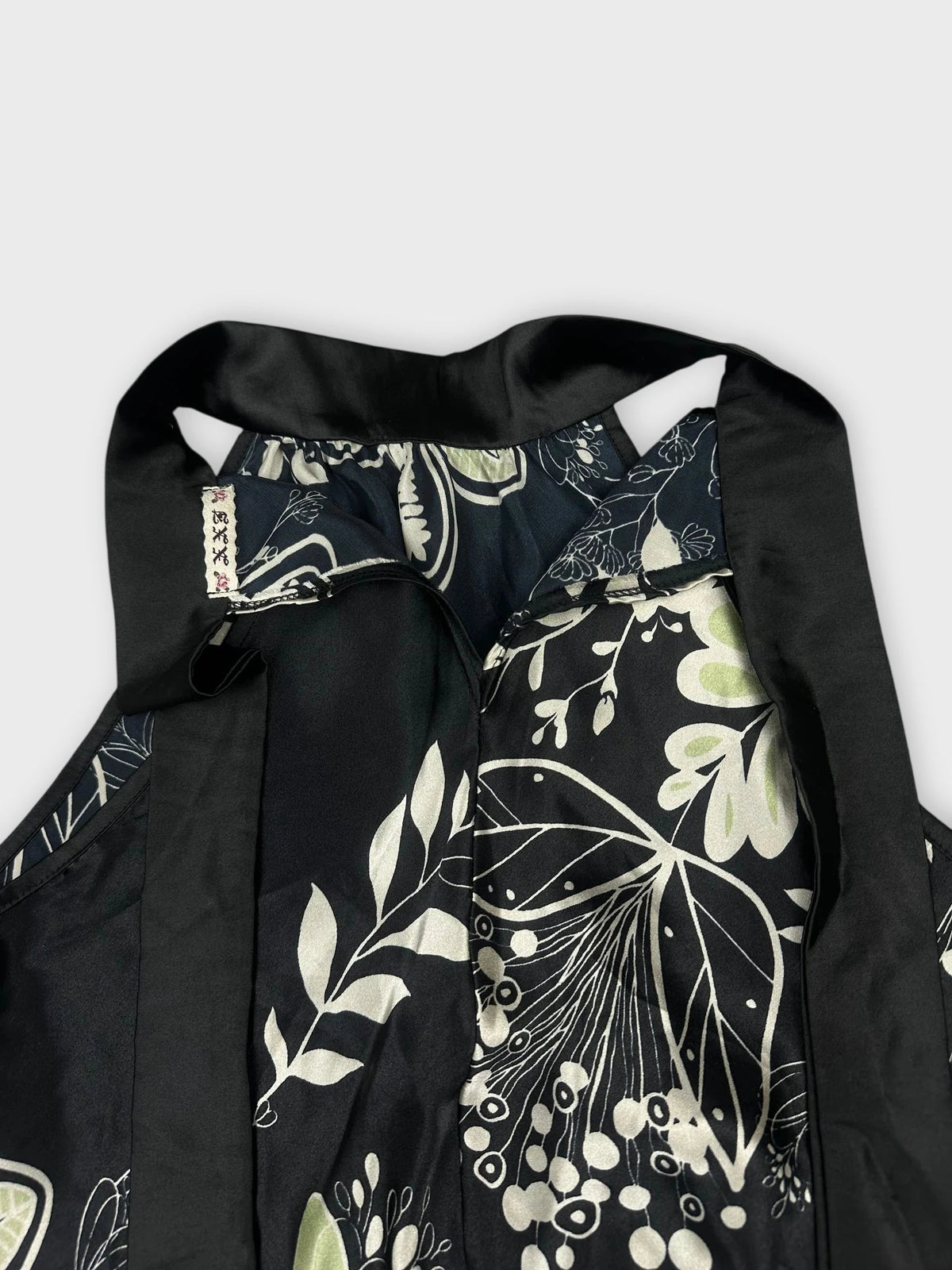 Detail view of floral halter top in black with green botanical print.