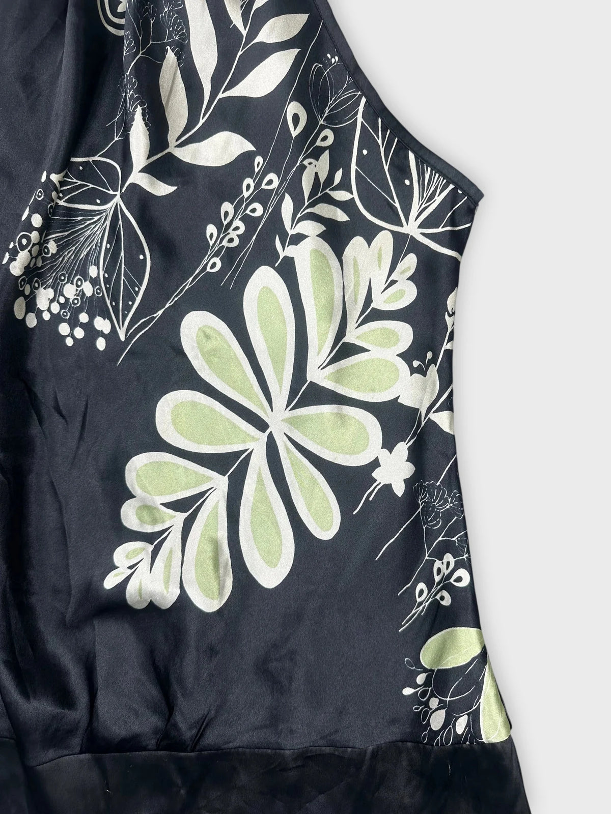 Detail view of floral satin halter top in black with green patterns