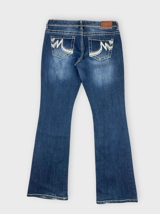 Flared denim jeans in blue with distressed pockets back view