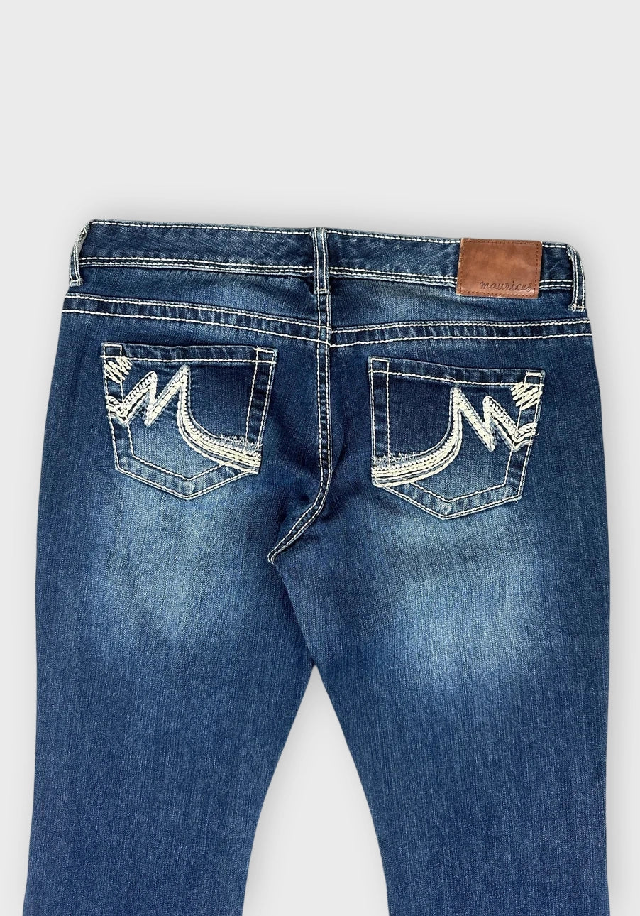 Detail view of flared denim jeans in dark blue with distressed pockets.
