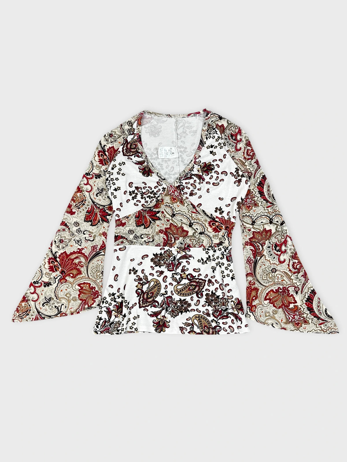 Detail view of a floral paisley print long-sleeve top in white and red.