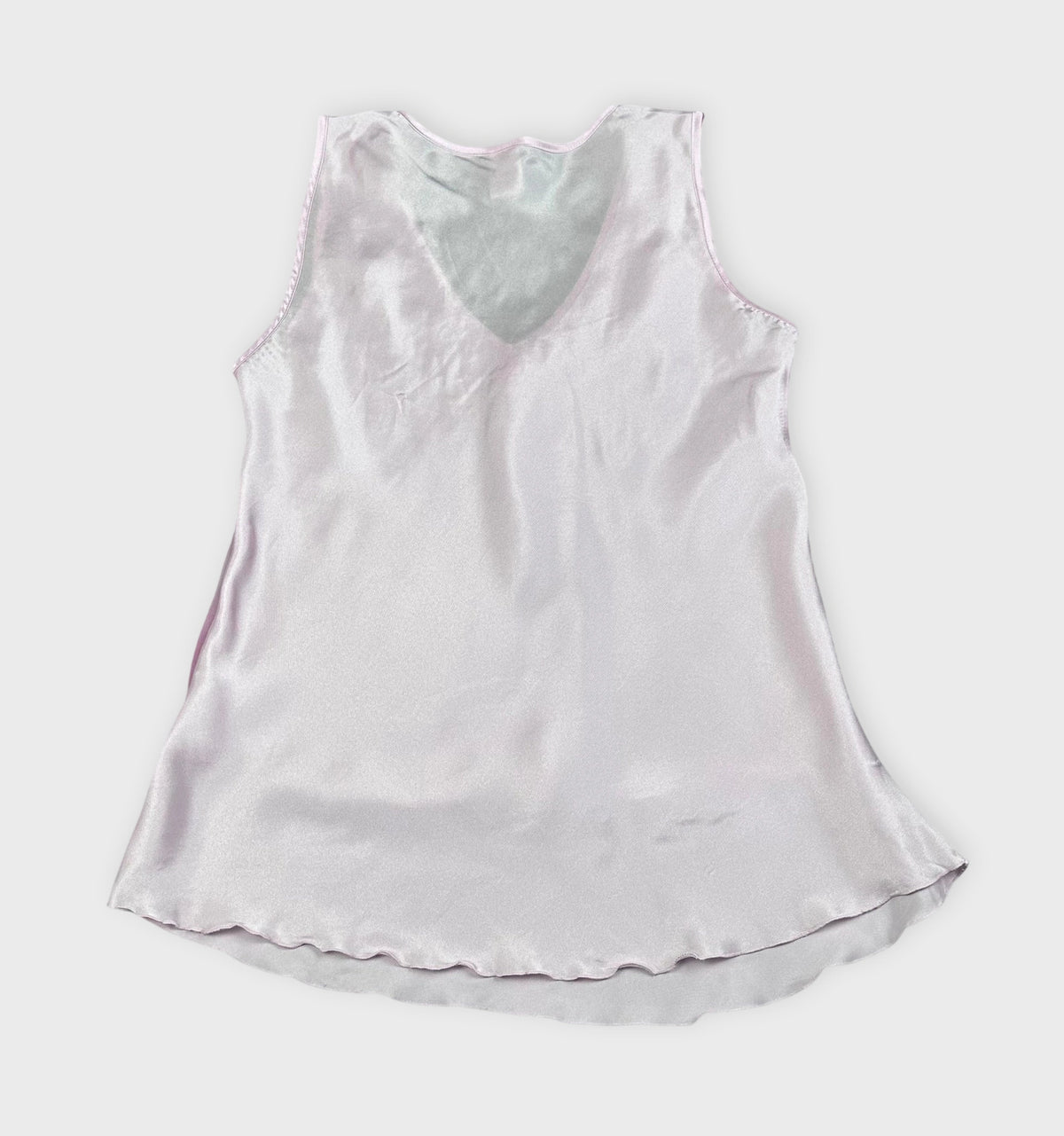 Back view of a sleeveless pink silk top featuring a V-neck and soft drape.