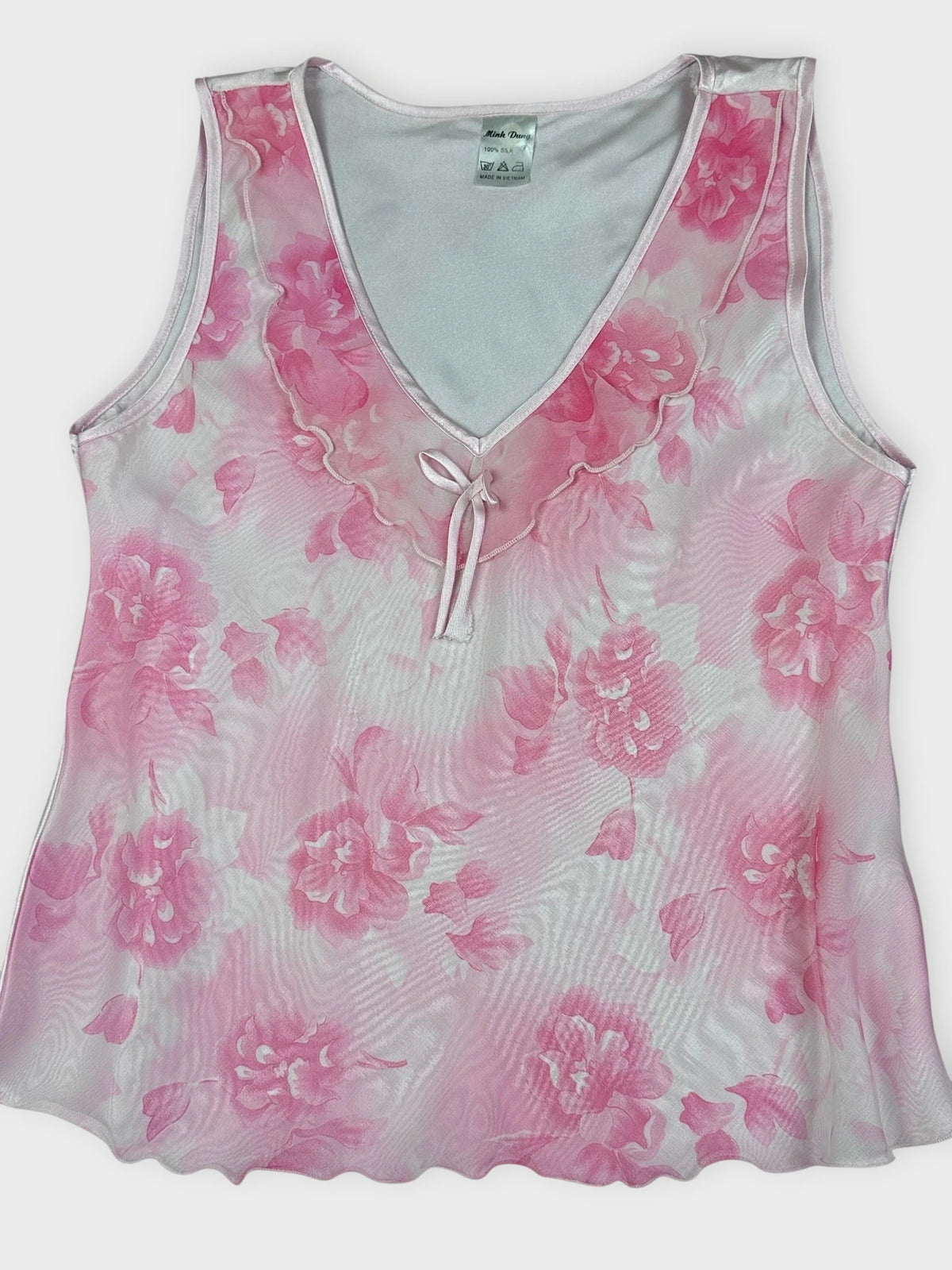 Detail view of pink floral silk sleeveless top with a tie detail.