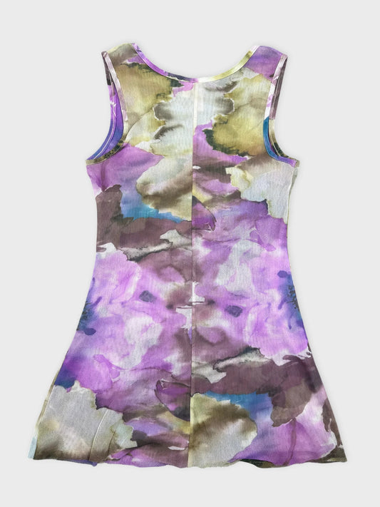 Back view of a floral print sleeveless dress in purple with ruffles.