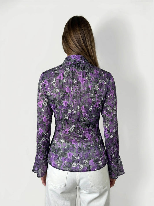Back view of a floral ruffle blouse in purple with bell sleeves.