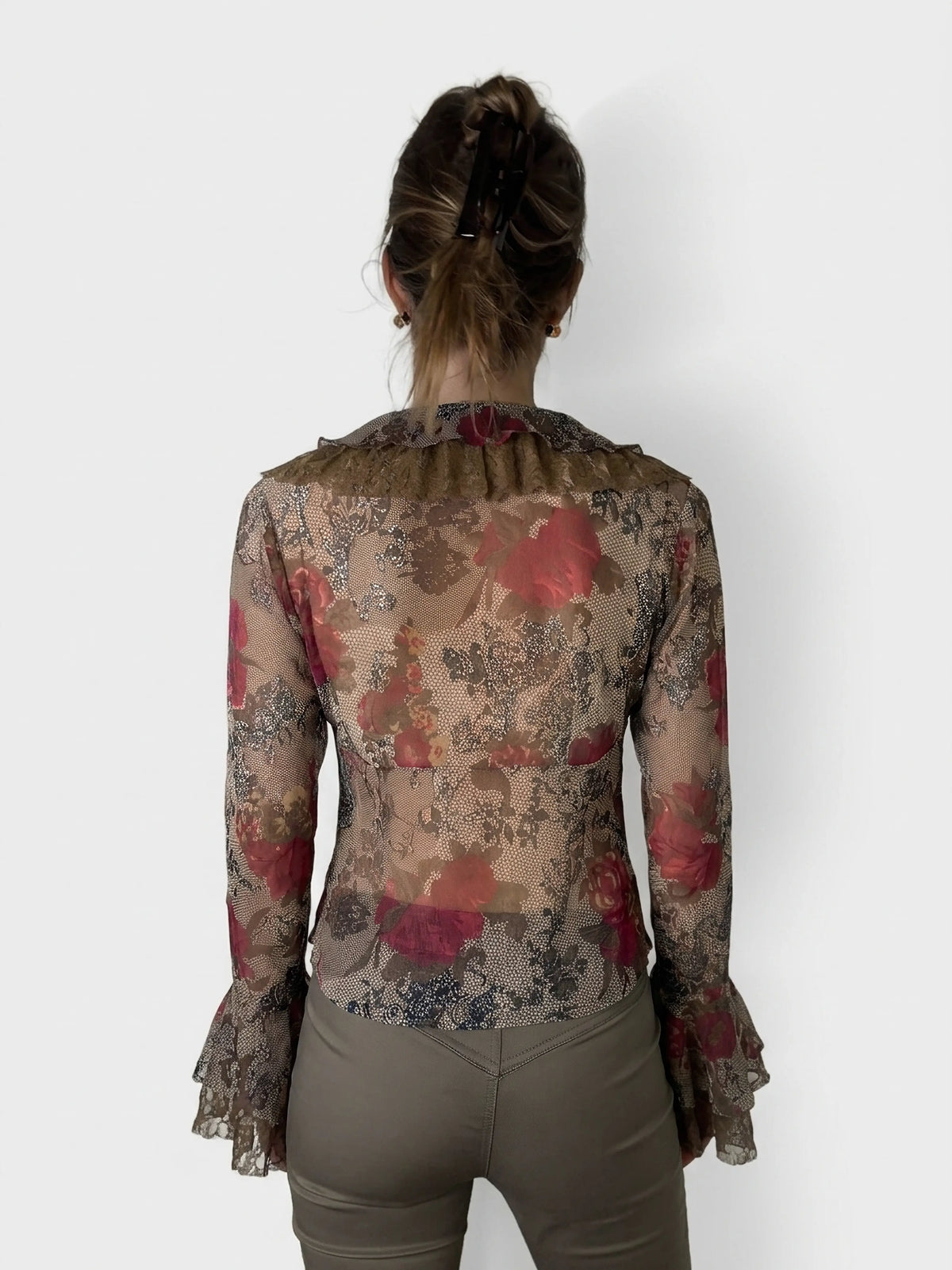 Back view of a floral ruffled top with sheer sleeves in brown and red.