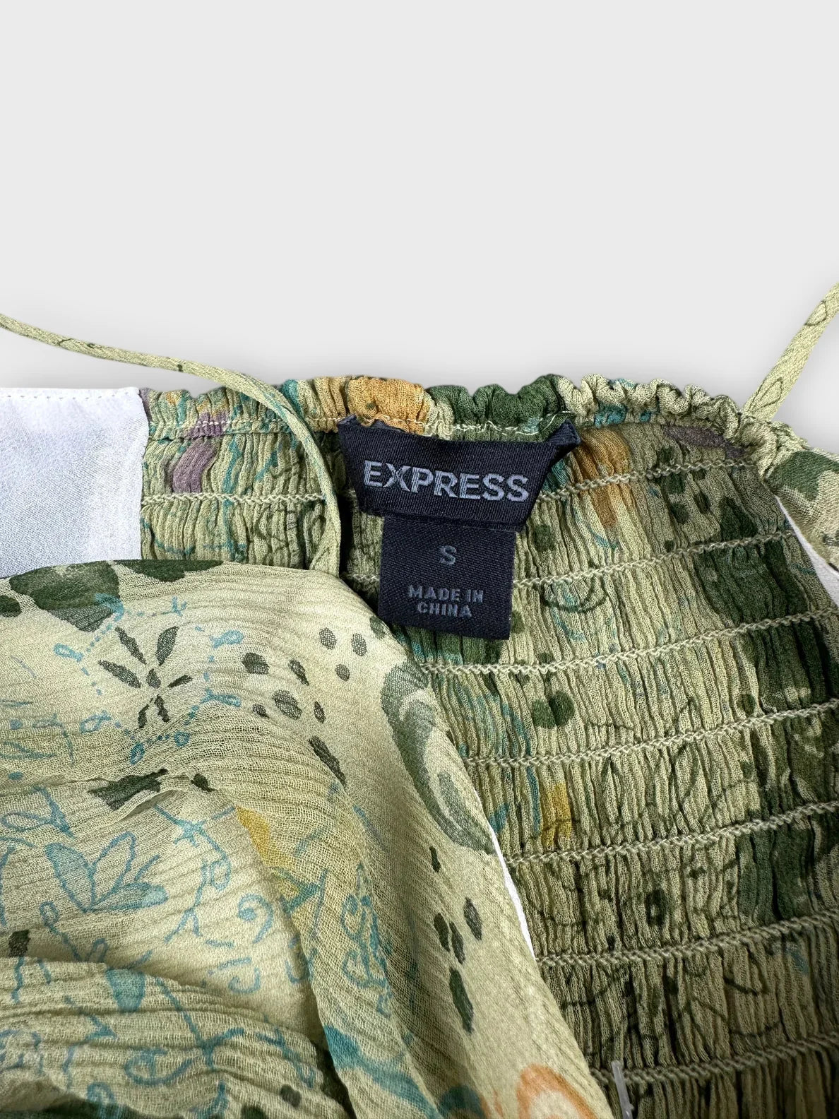 Detail view of floral silk cami top in green with ruched texture.