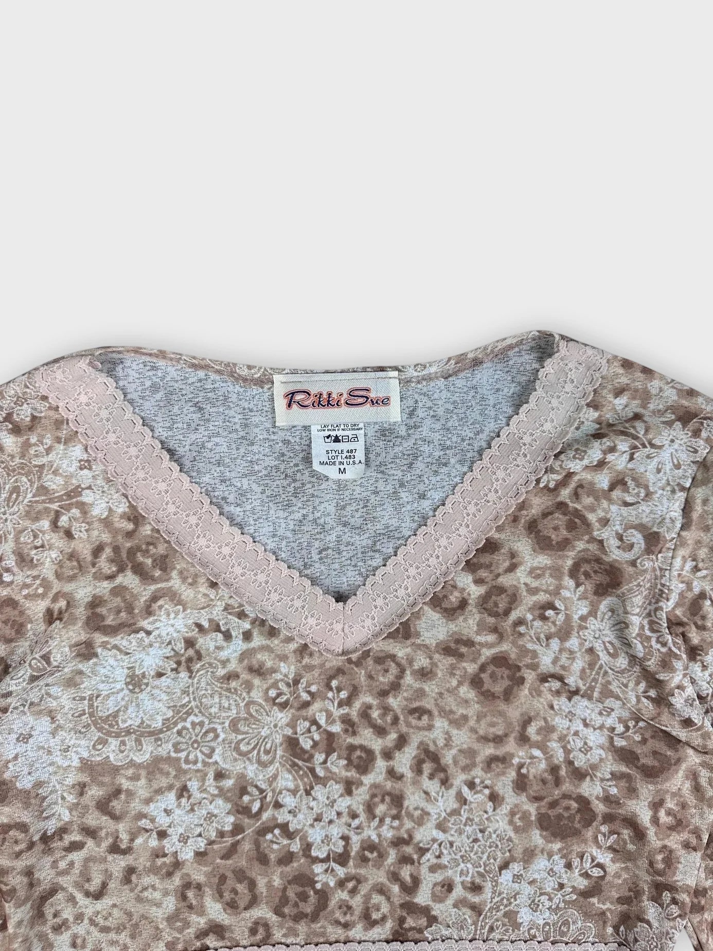 Detail view of floral V-neck top in earthy tones with lace trim.