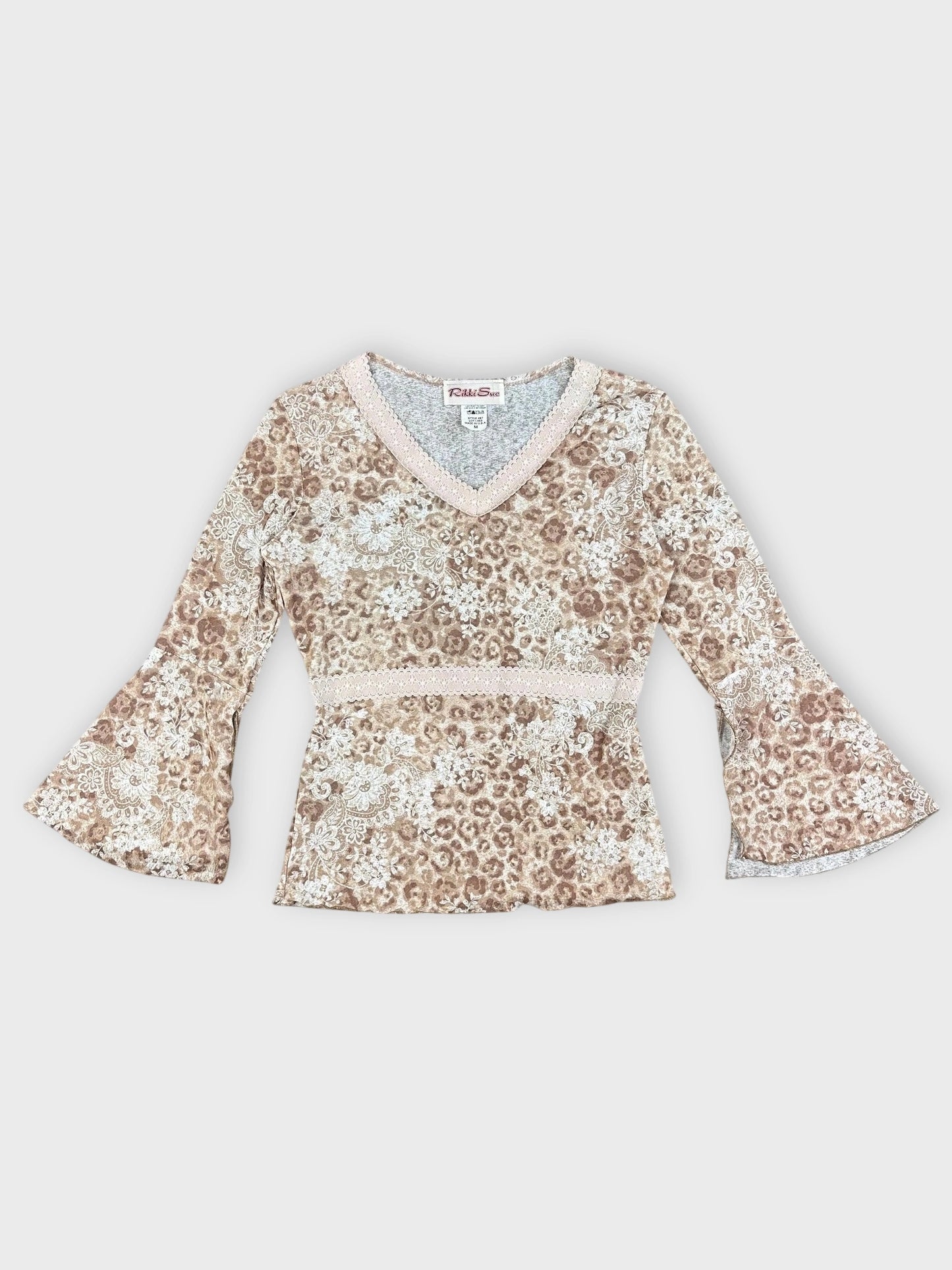 Detail view of floral v-neck bell sleeve top in earthy tones with lace trim.