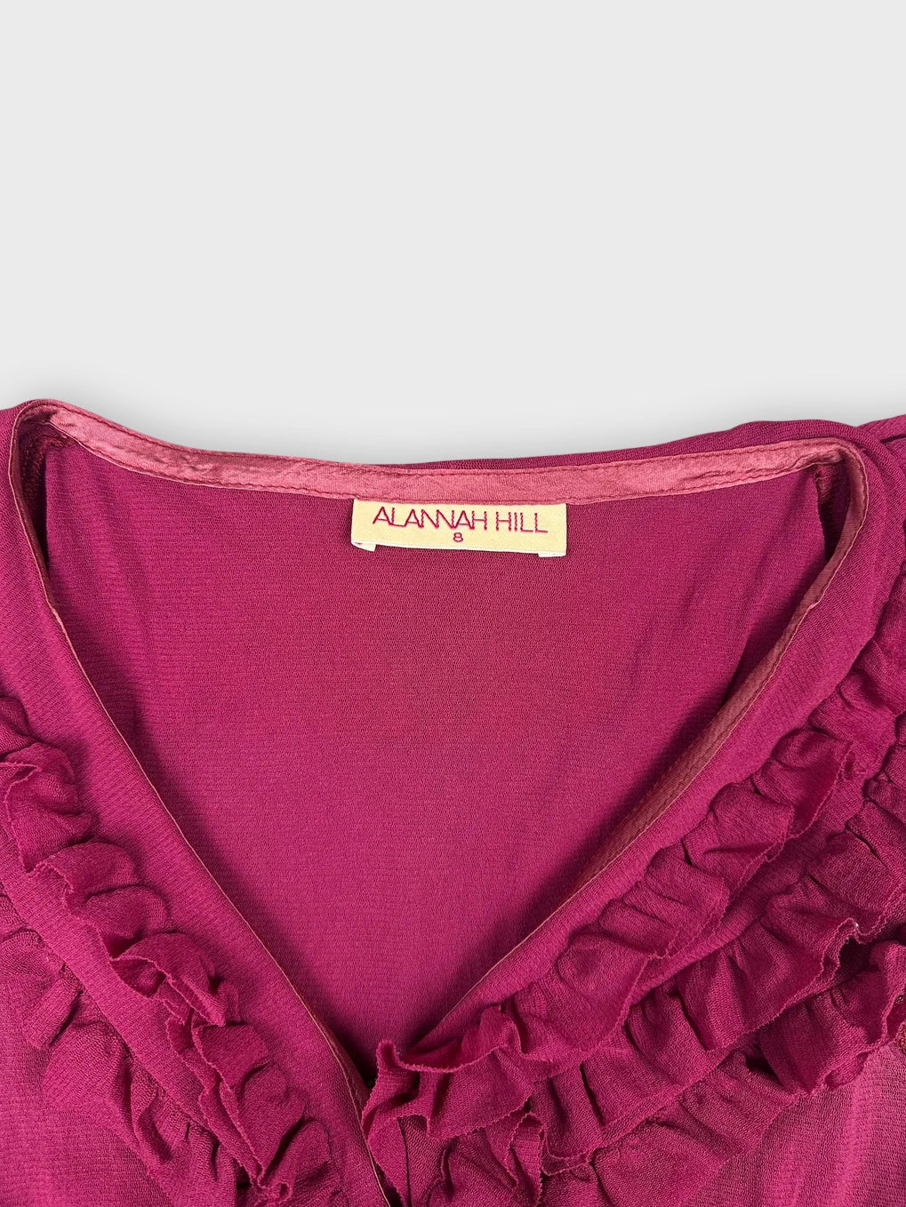 Detail view of a fuchsia ruffled top featuring a V-neckline.