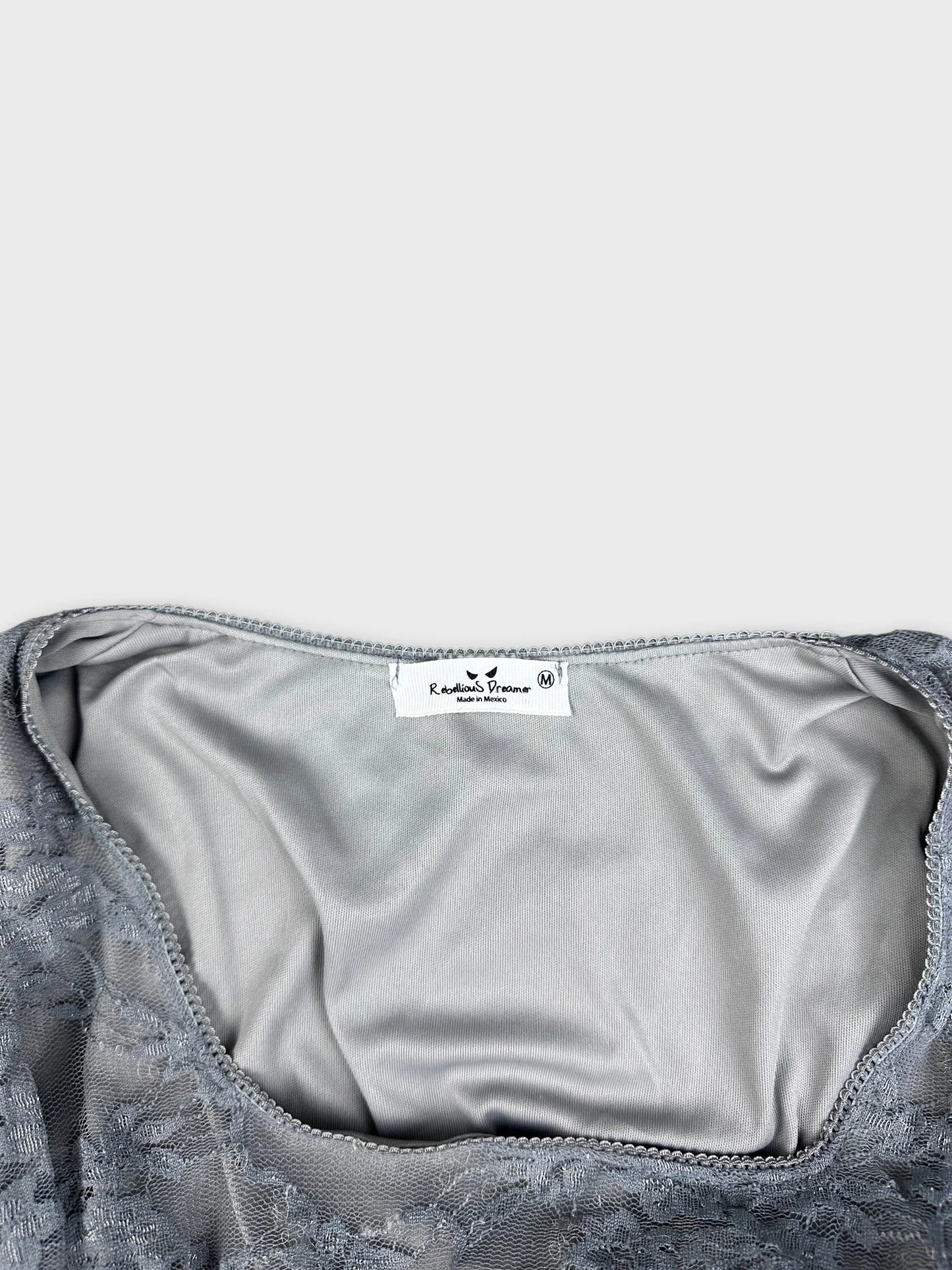 Detail view of gray long-sleeve top showcasing lace trim and inner lining.