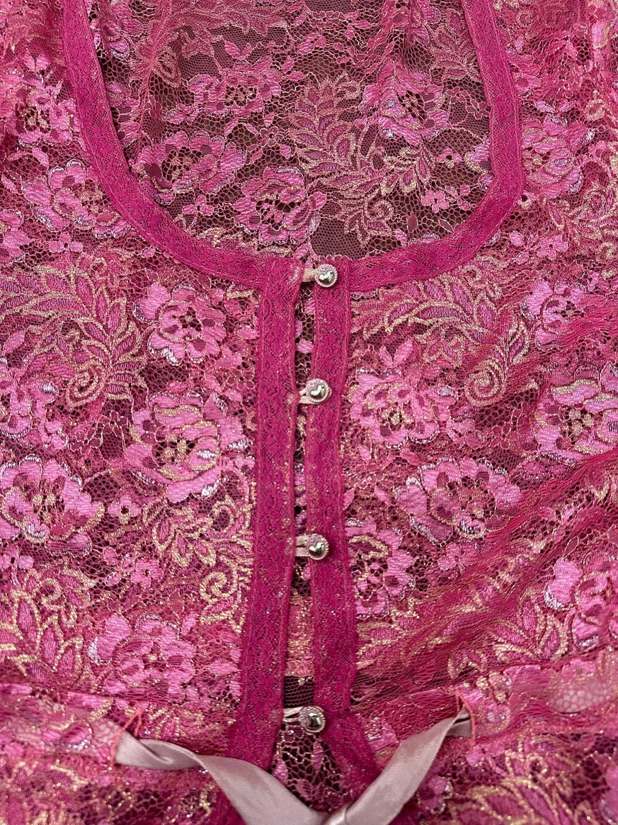 Detail view of a pink lace top with button closure and satin trim.