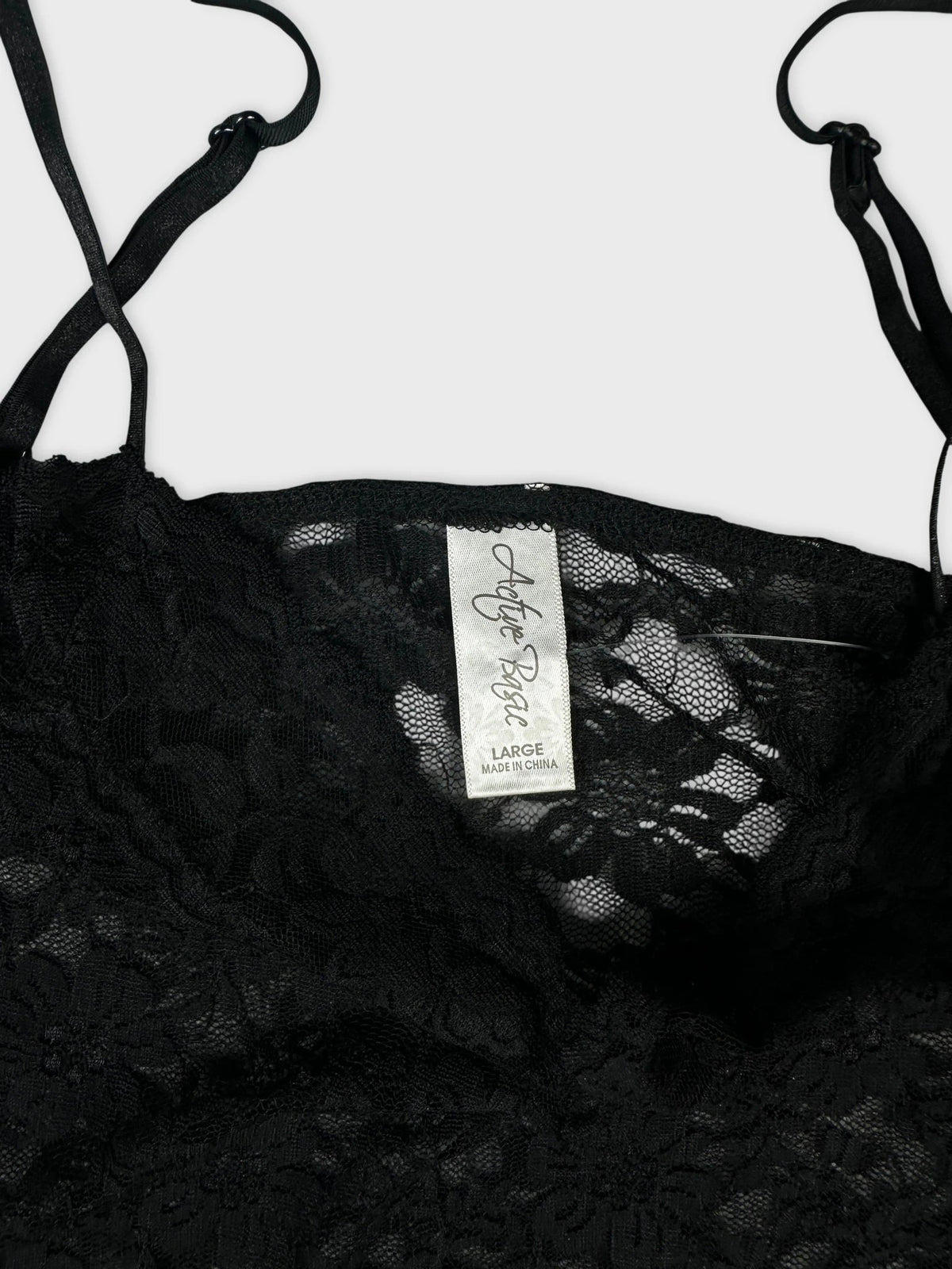 Detail view of a black lace cami top with floral design.