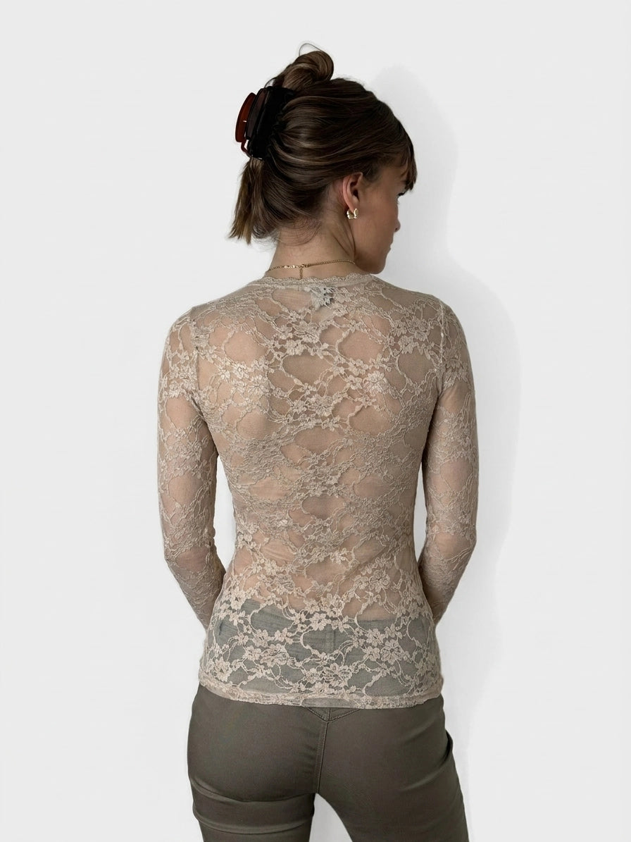 Back view of a lace long sleeve top in beige with sheer detail.