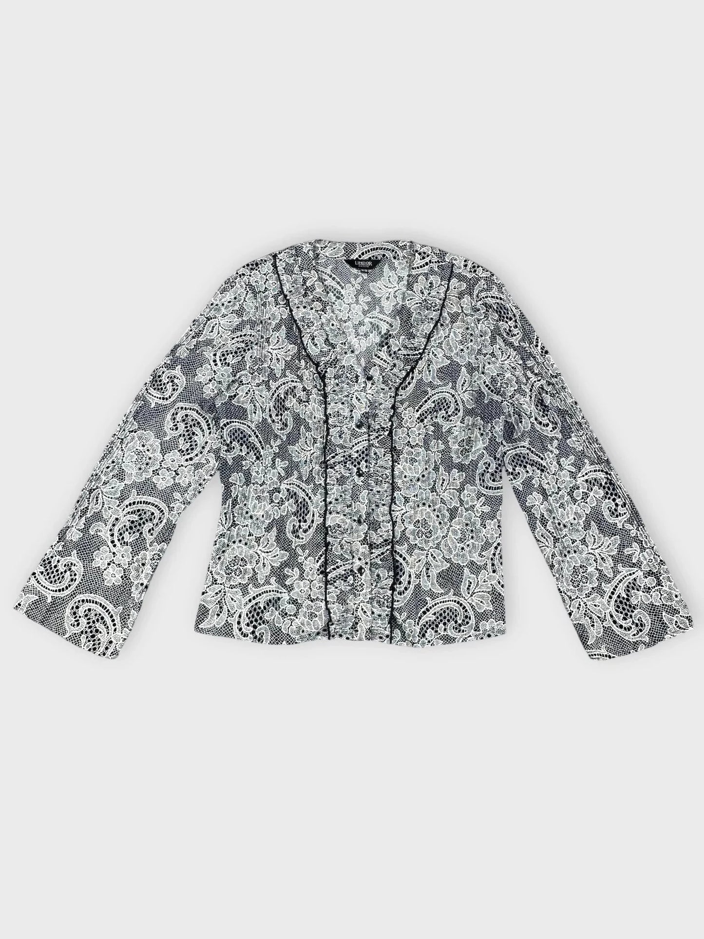 Lace-print button-up blouse in black and white detail view with ruffle trim.