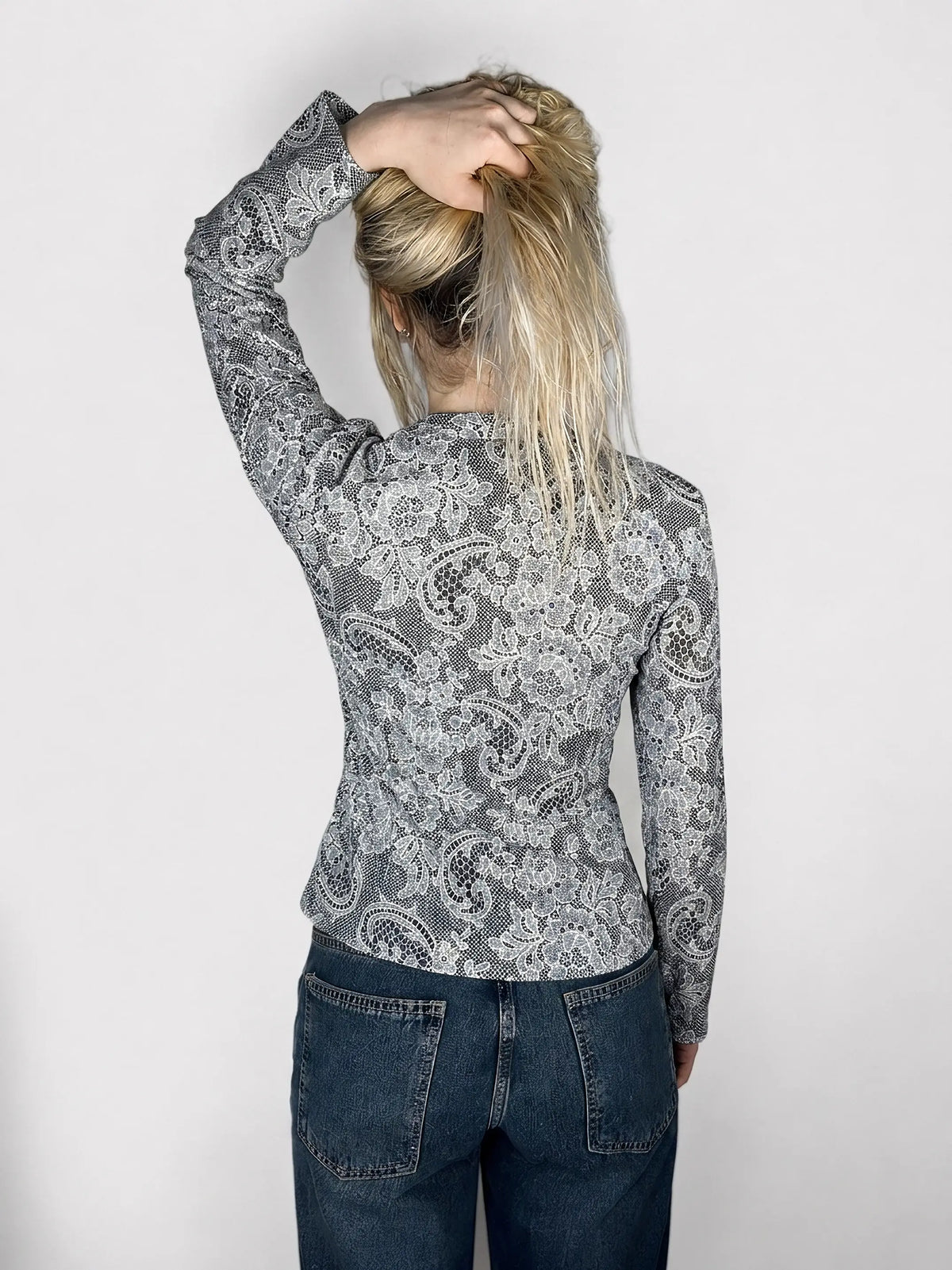 Back view of a black and white lace-print ruffled blouse.
