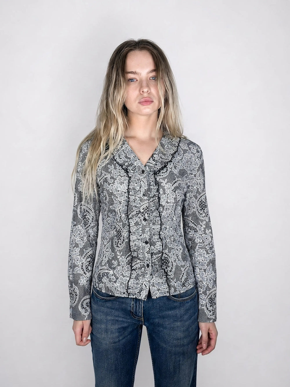 Front view of a lace-print ruffled button-up blouse in black and white.