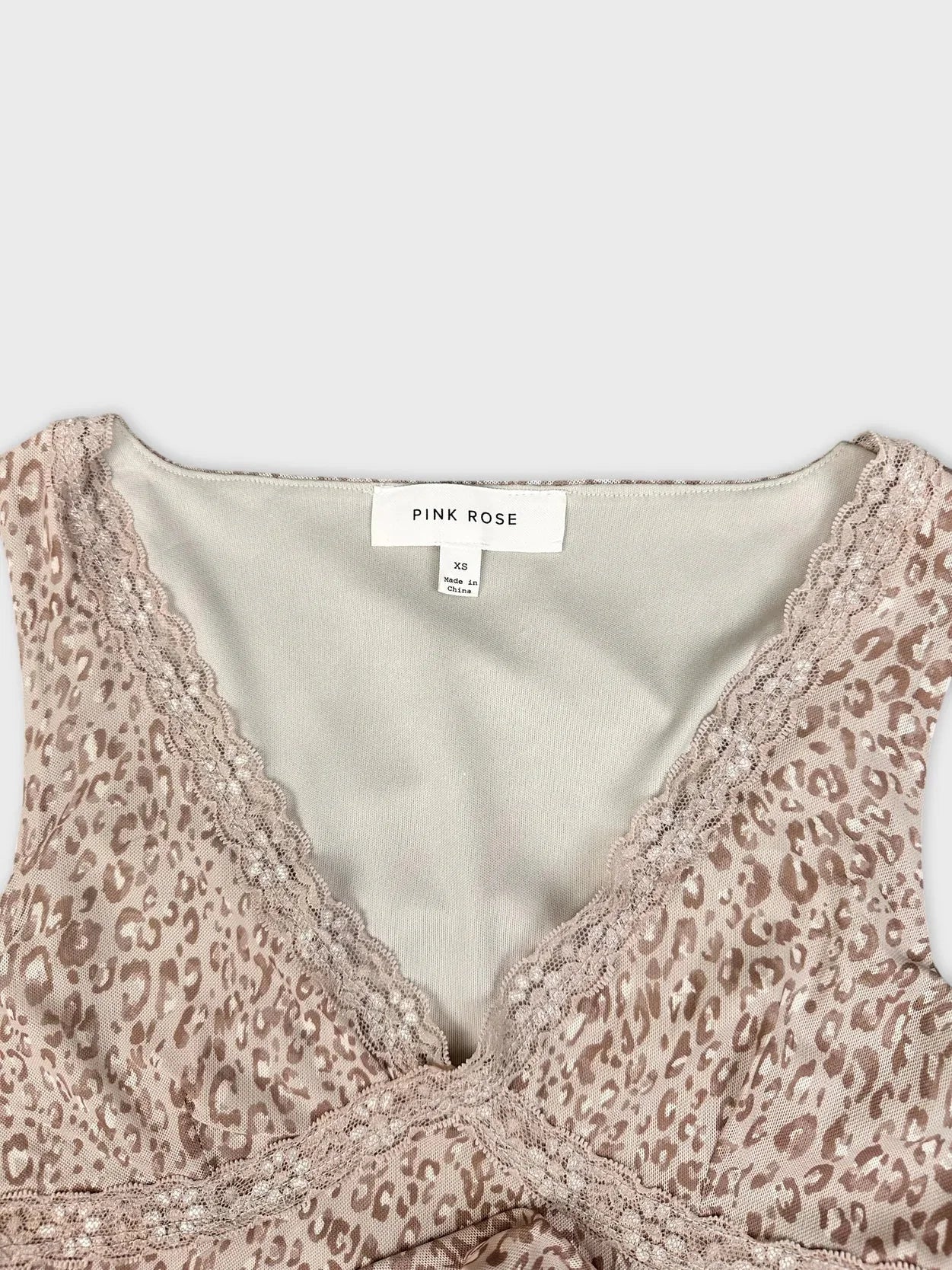 Detail view of beige leopard print short sleeve top with lace trim.