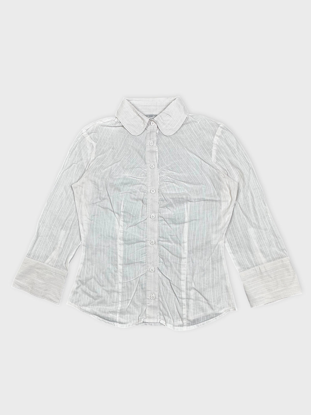 Detail view of a white long-sleeve shirt with vertical stripes.