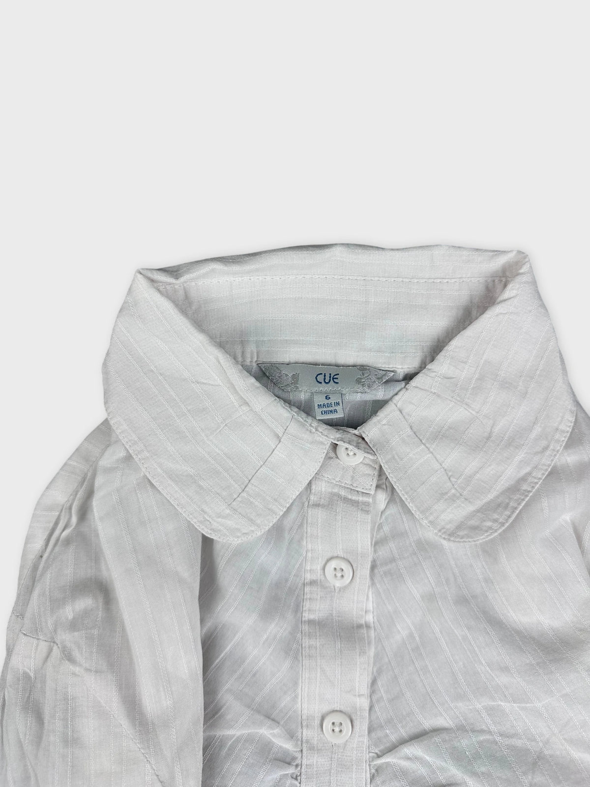Detail view of a white shirt featuring a classic collar and button placket.